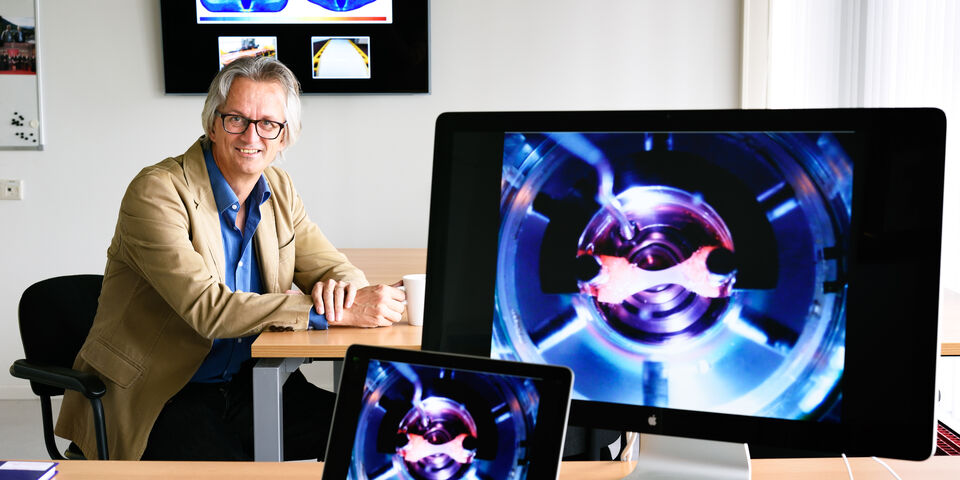 Cees Oomens. Op de monitor: in het lab gekweekt spiertje voor onderzoek naar schade door druk en zuurstofgebrek. Foto | Bart van Overbeeke