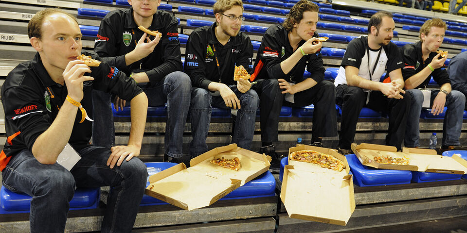Het team van Tech United onder leiding van Pieter van Zutven (links) heeft een korte lunchpauze met pizza's. l Foto Bart van Overbeeke