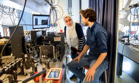 Gedeelde eerste auteurs Elham Fadaly (links) en Alain Dijkstra (rechts) bedienen een optische opstelling om licht-emissie te meten. Foto | Sicco van Grieken, SURF