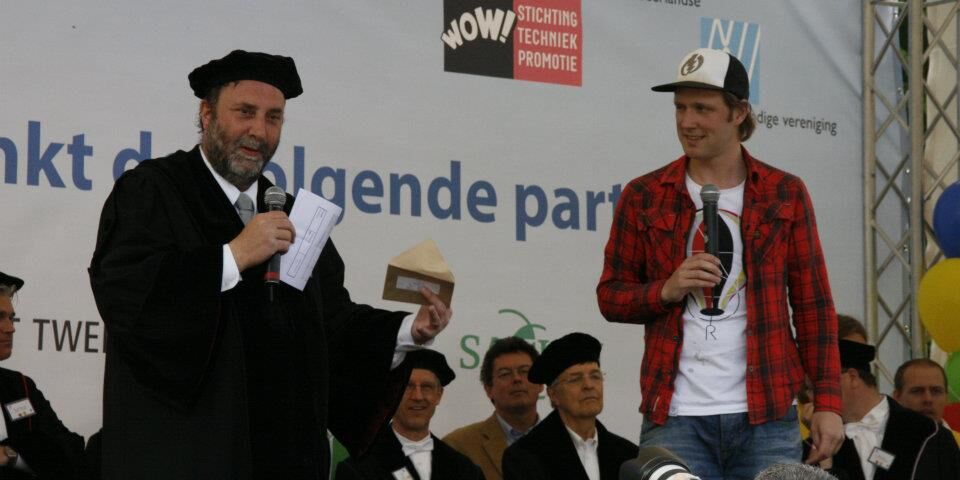TU/e-hoogleraar Gerrit Kroesen op het podium met Bart Meijer, presentator van Het Klokhuis, tijdens het Techniek Toernooi in het Openluchtmuseum in Arnhem waar de samenwerking bekend werd gemaakt.