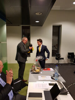 Jo van Ham ontvangt een fles wijn en bijpassende glazen tijdens zijn laatste optreden in de vergadering met de U-raad. Foto | Han Konings