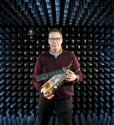 Mark Bentum met een nano-satelliet. Foto | Bart van Overbeeke