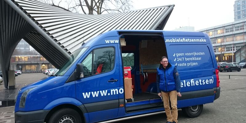 Mobiele fietsenmaker John Hermans voor zijn busje.