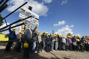 FOM-personeel bij het hijsen van het bouwbord voor het nieuwe pand. Foto | Bart van Overbeeke