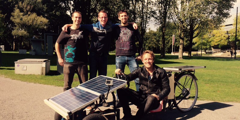 Studenten Frank Rams, Jelmer van de Wiel en Arjo van der Ham, met op de zonnewagen presentator Bart Meijer.